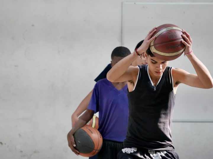 Estudiante lanzando un balón de básquetbol en el gimnasio