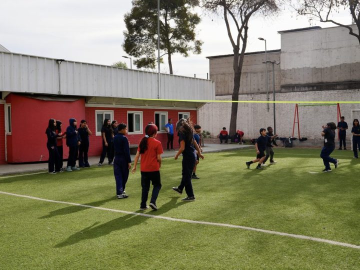 Estudiantes jugando fútbol en la cancha de pasto sintético